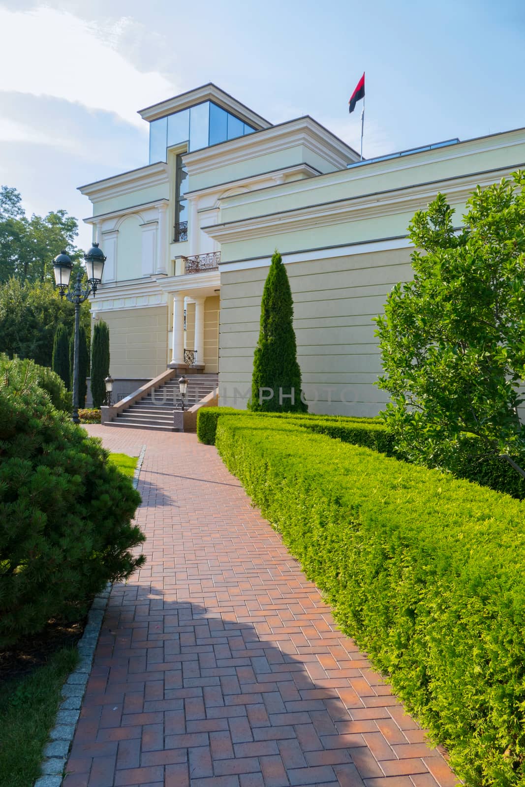 A paved stone path to the building next to a well-groomed lawn