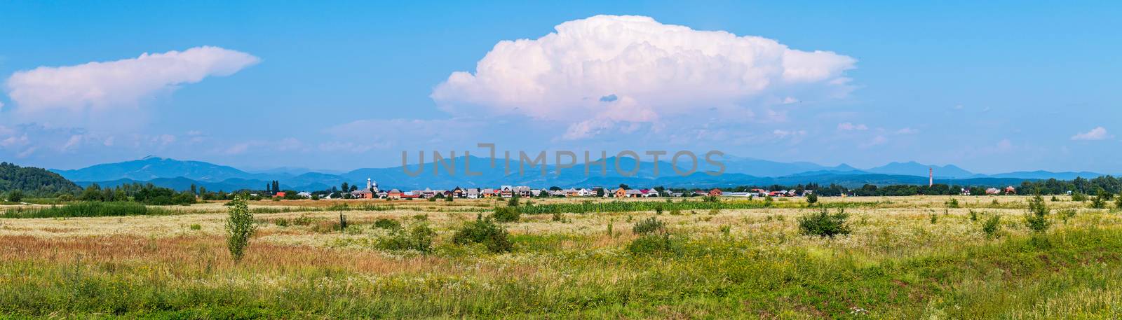 A huge white cloud against the blue sky settled over a small rural mountain village