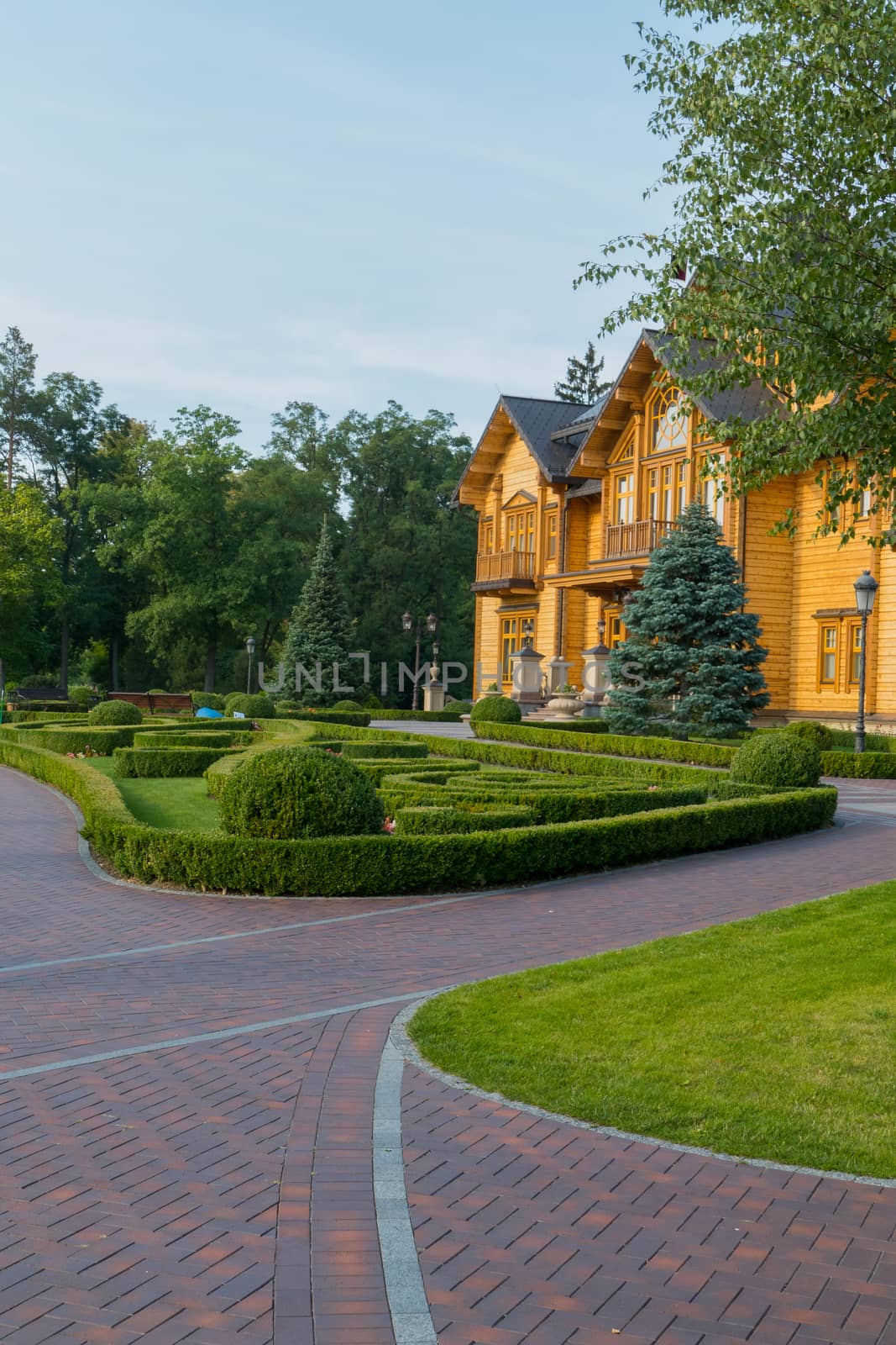 Ornaments made from shaved boxwood bushes on a lawn in front of a wooden house. Mezhygirya Ukraine by Adamchuk