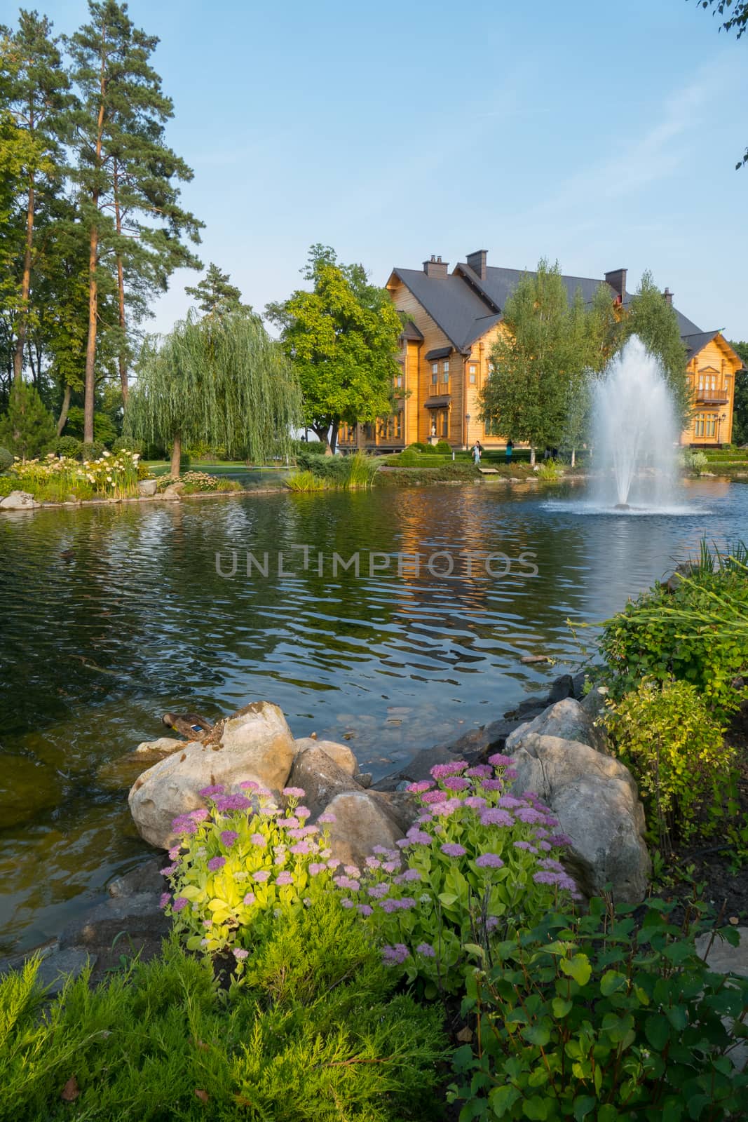 A picturesque view of a large decorative lake with a fountain in the middle and flower beds on either side of it