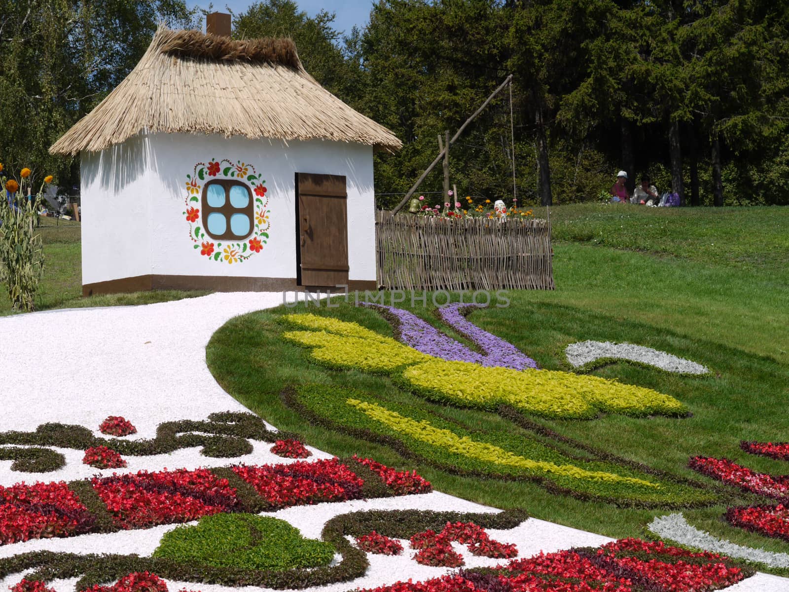 snow-white cottage under thatched roof made in the park in national traditions