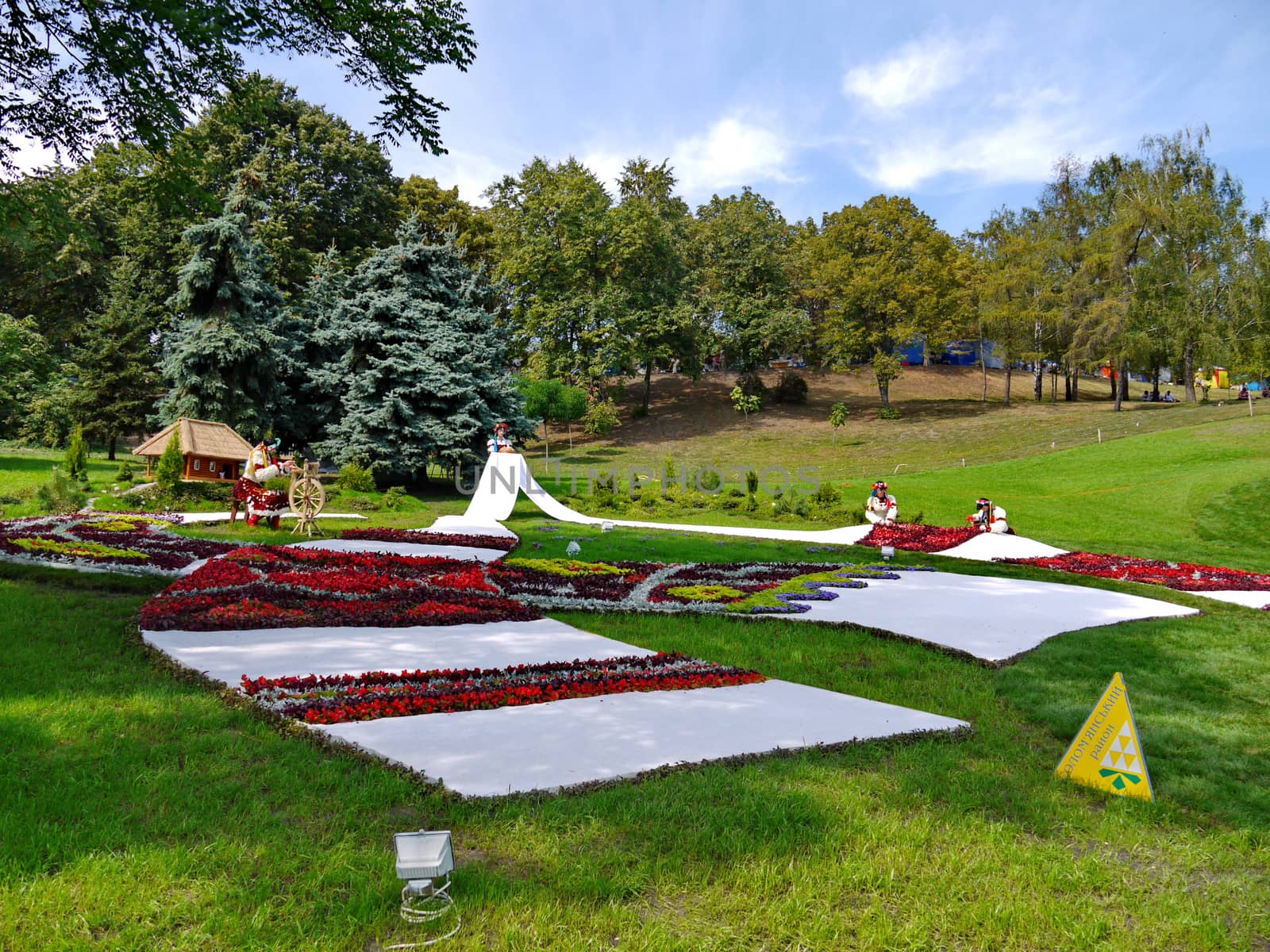 decorative flowerbeds in the form of embroidered towels with Ukrainian girls in wreaths and backgrounds of green grass