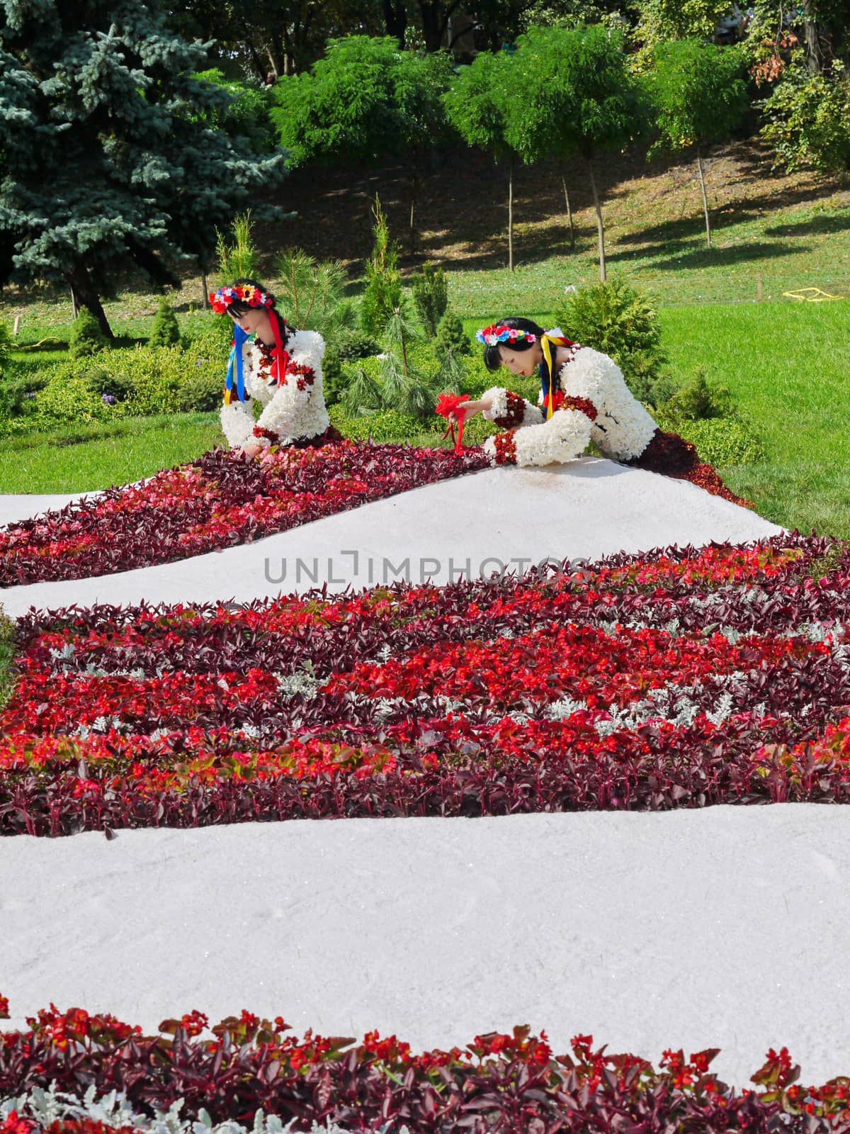 Girls in ethnic Ukrainian clothes from flowers near flower beds on a white background in a pack zone.