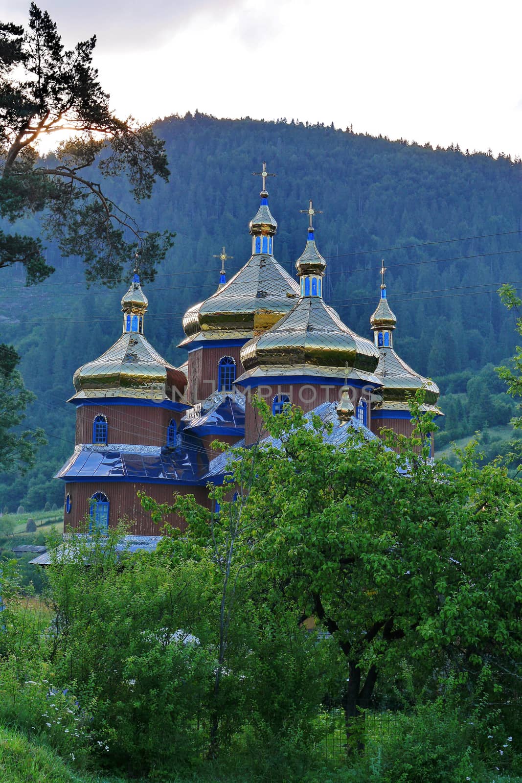 Beautiful church church with large golden domes on the background of huge green mountains