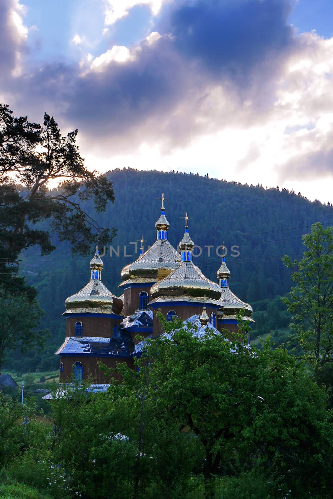 Beautiful church with gold-casting domes located among the green nature of the mountainous terrain.