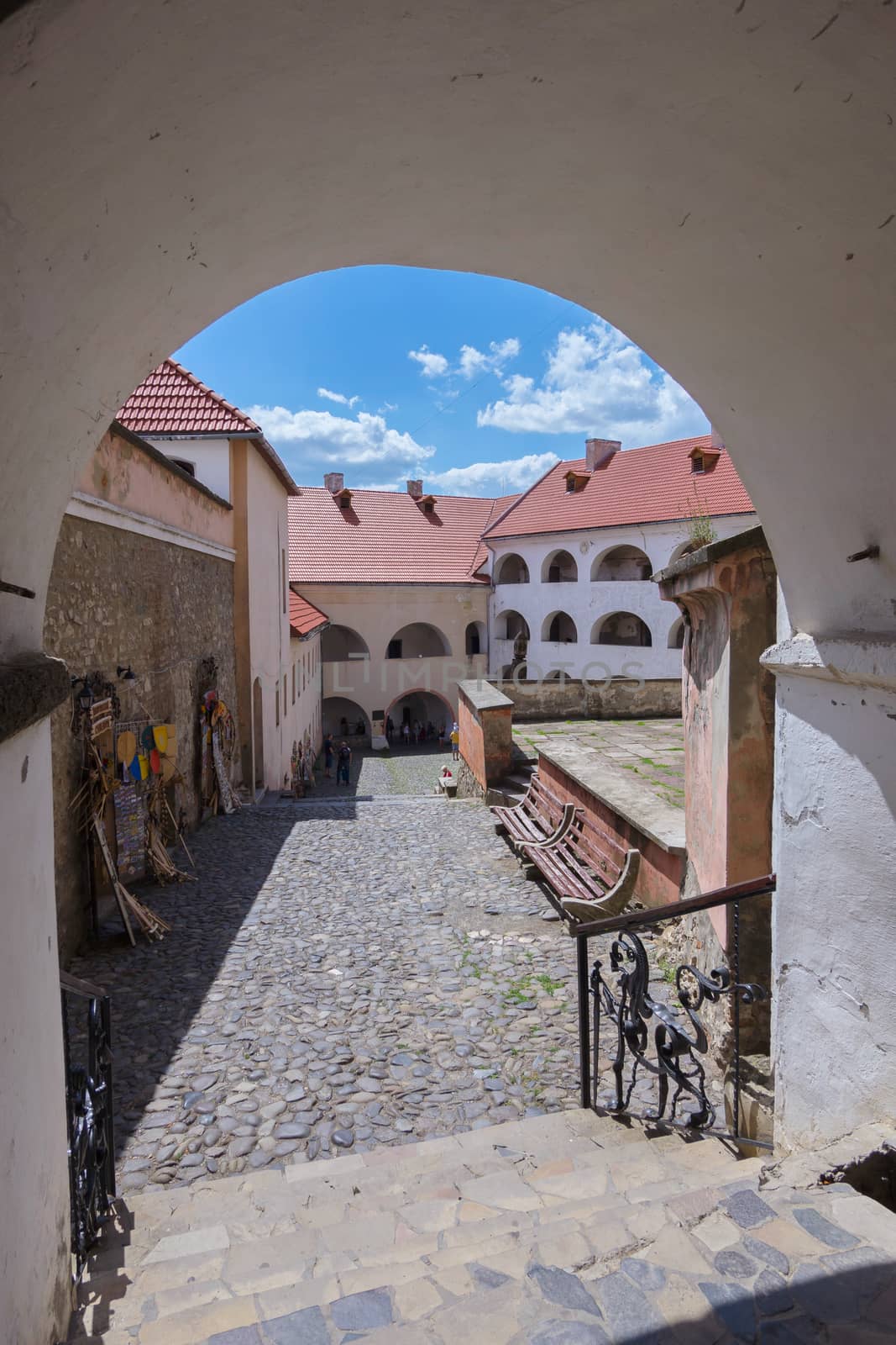 Large white arch with steps leading to the square with benches, souvenirs and beautiful architectural houses