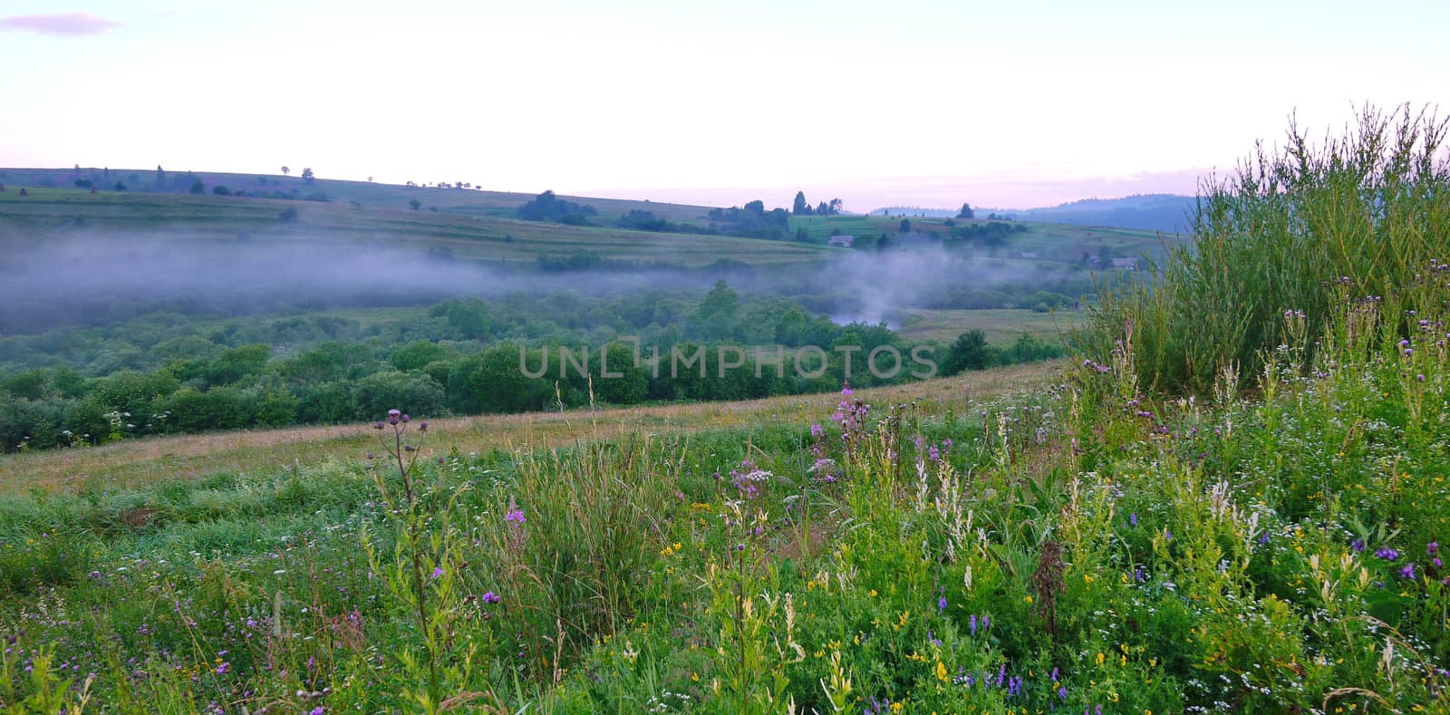 The beam between the green hills is covered with smoke. Probably someone cooks porridge at the stake