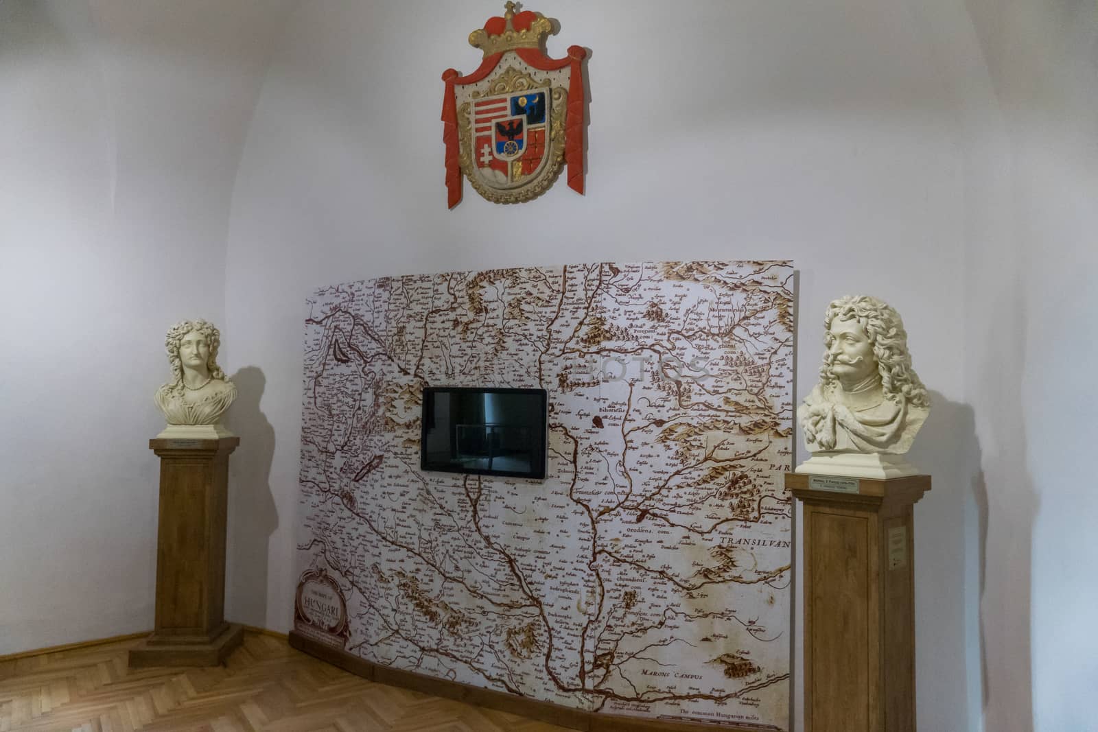 An image of a map with a coat of arms above it and busts of famous historical figures