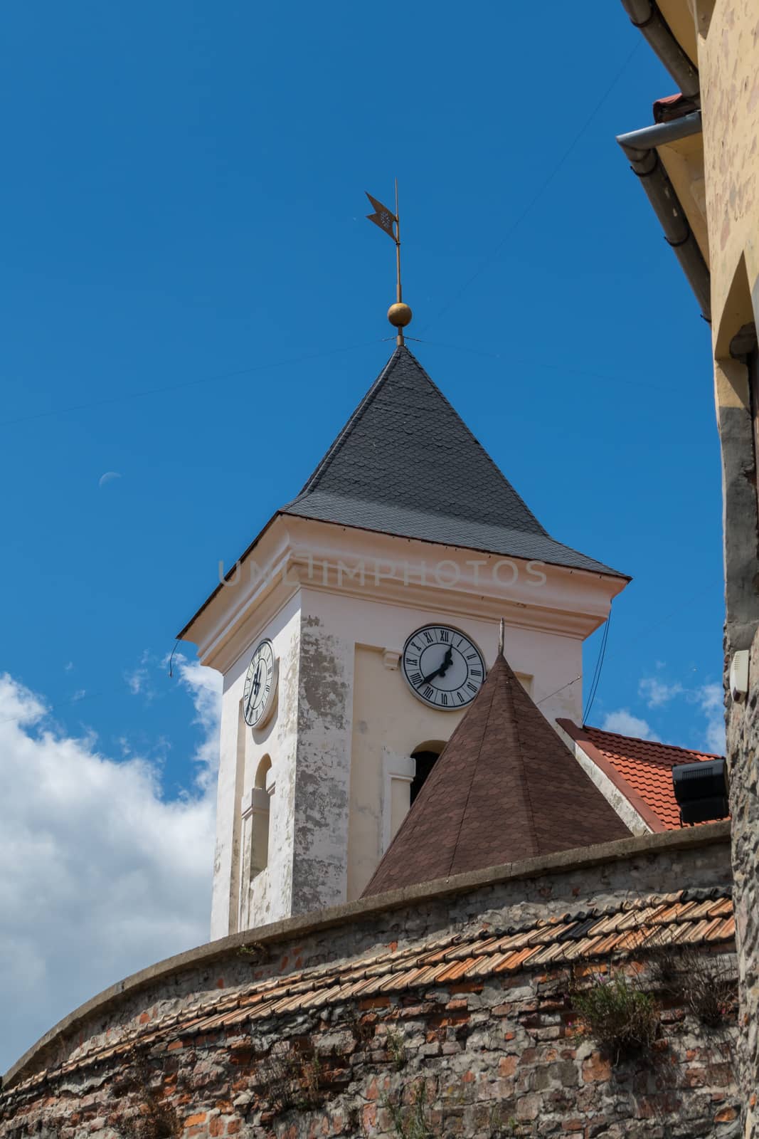 an ancient gentle pink chapel with a black tile and a weather vane
