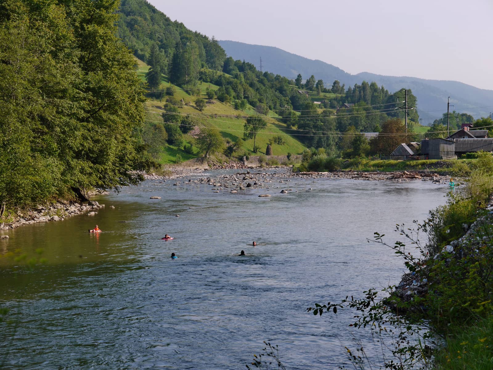 people bathing in the river on the background of mountains