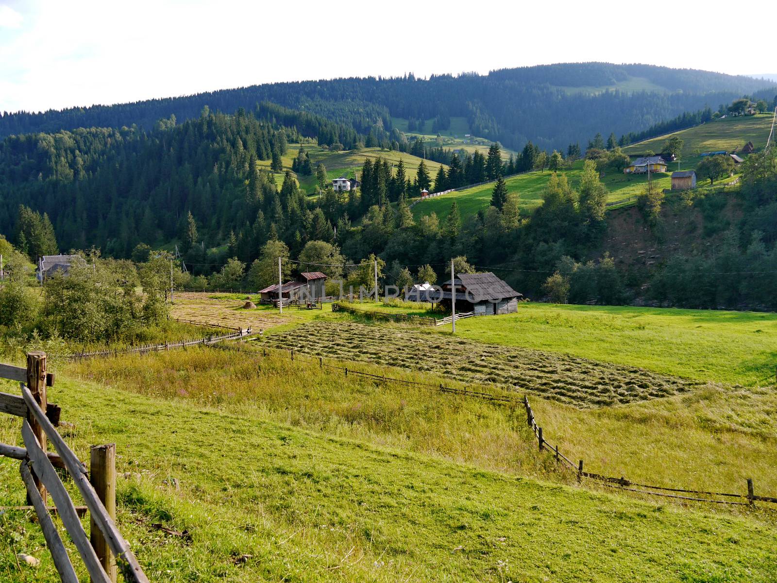 Authentic residential houses with old fences at the foot of a huge mountain in the background of a clear sky