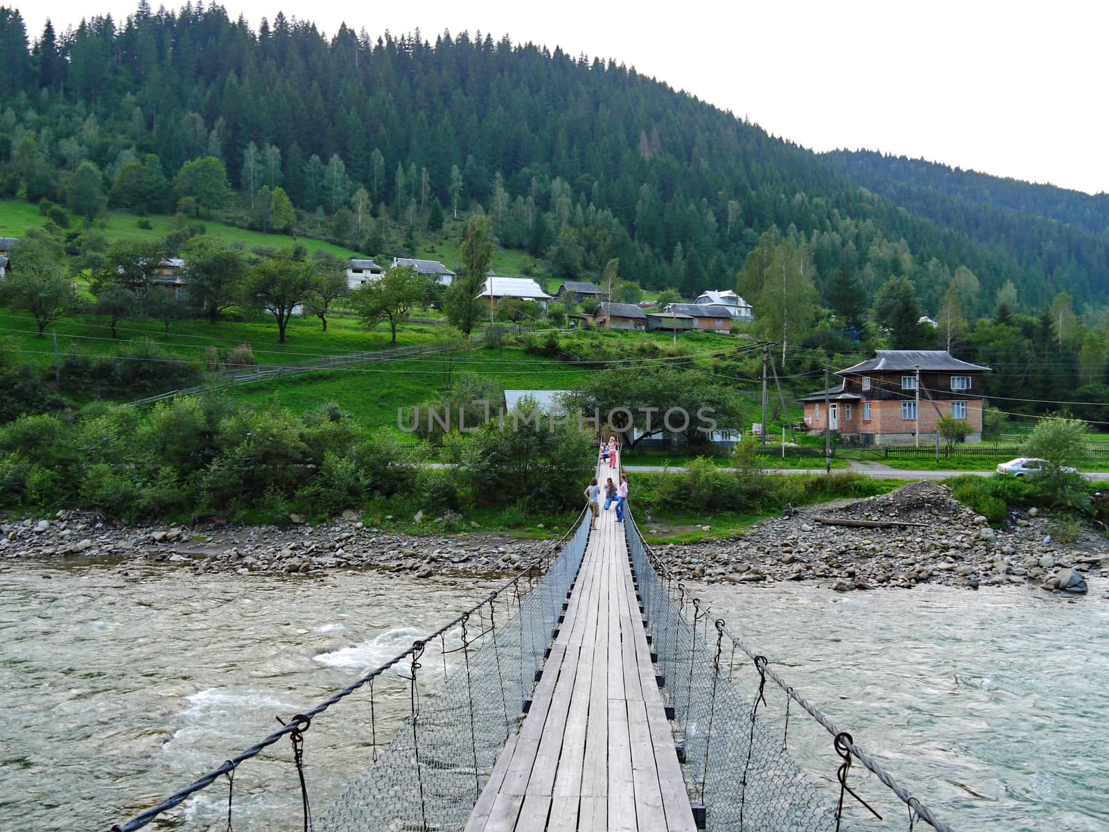 Suspended wooden bridge across a rugged little mountain river