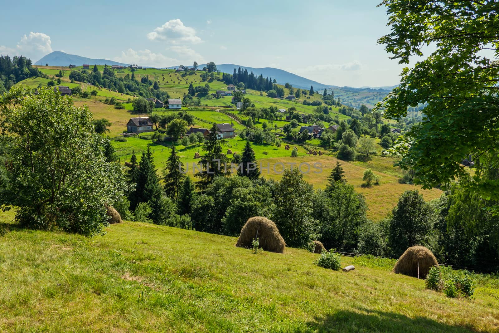 A picturesque view of a rural village located in the middle of green mountain ranges