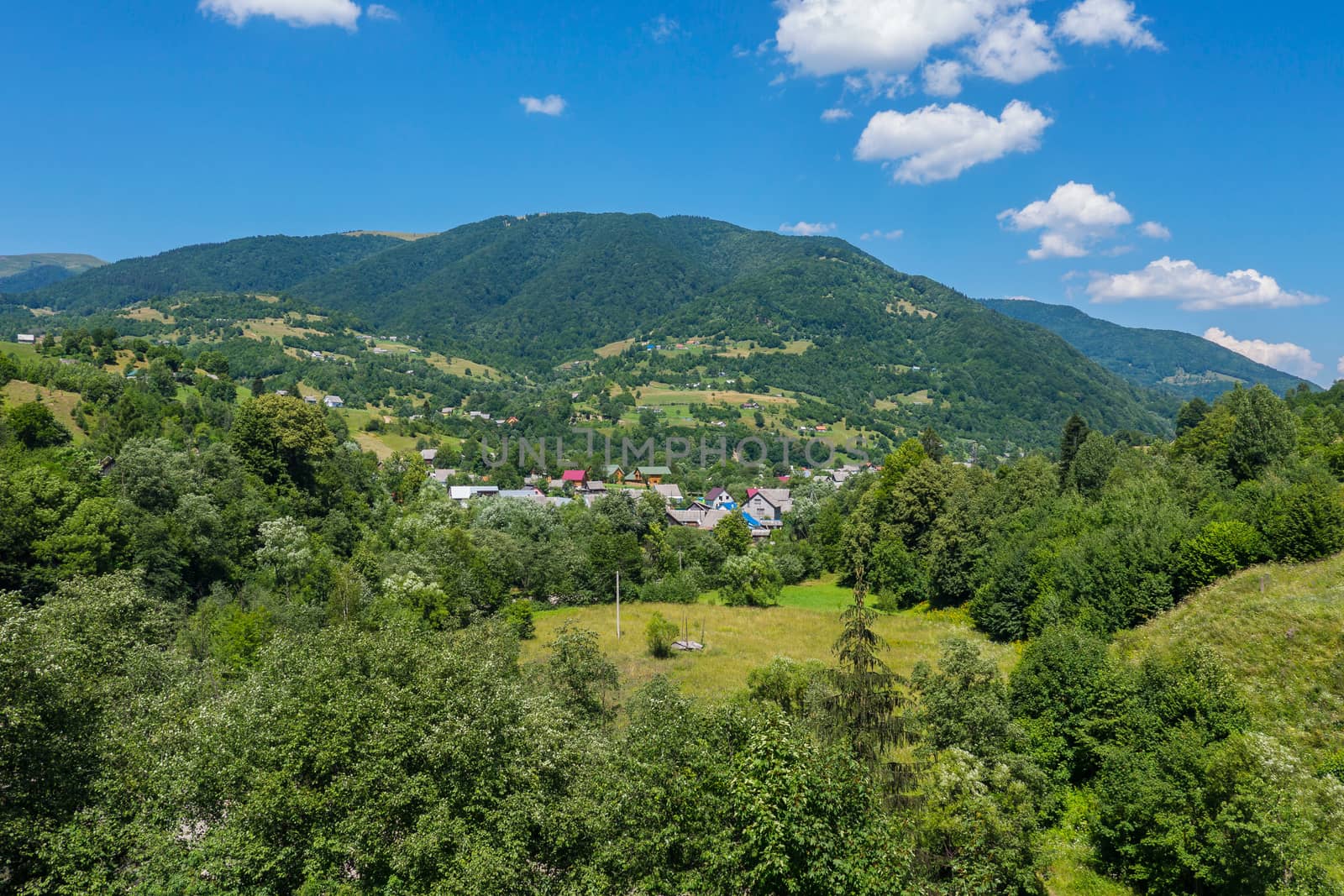 The village is situated among green trees of picturesque nature near a high mountain. by Adamchuk