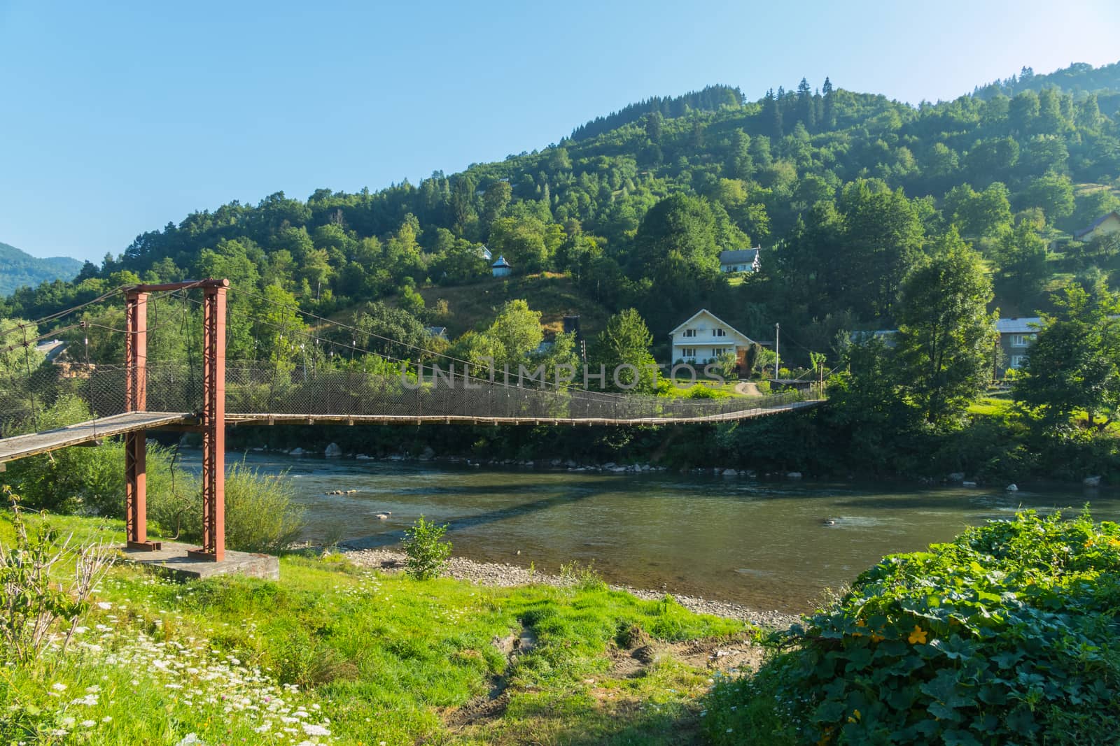 cloudless sky above the cable bridge over the mountain river