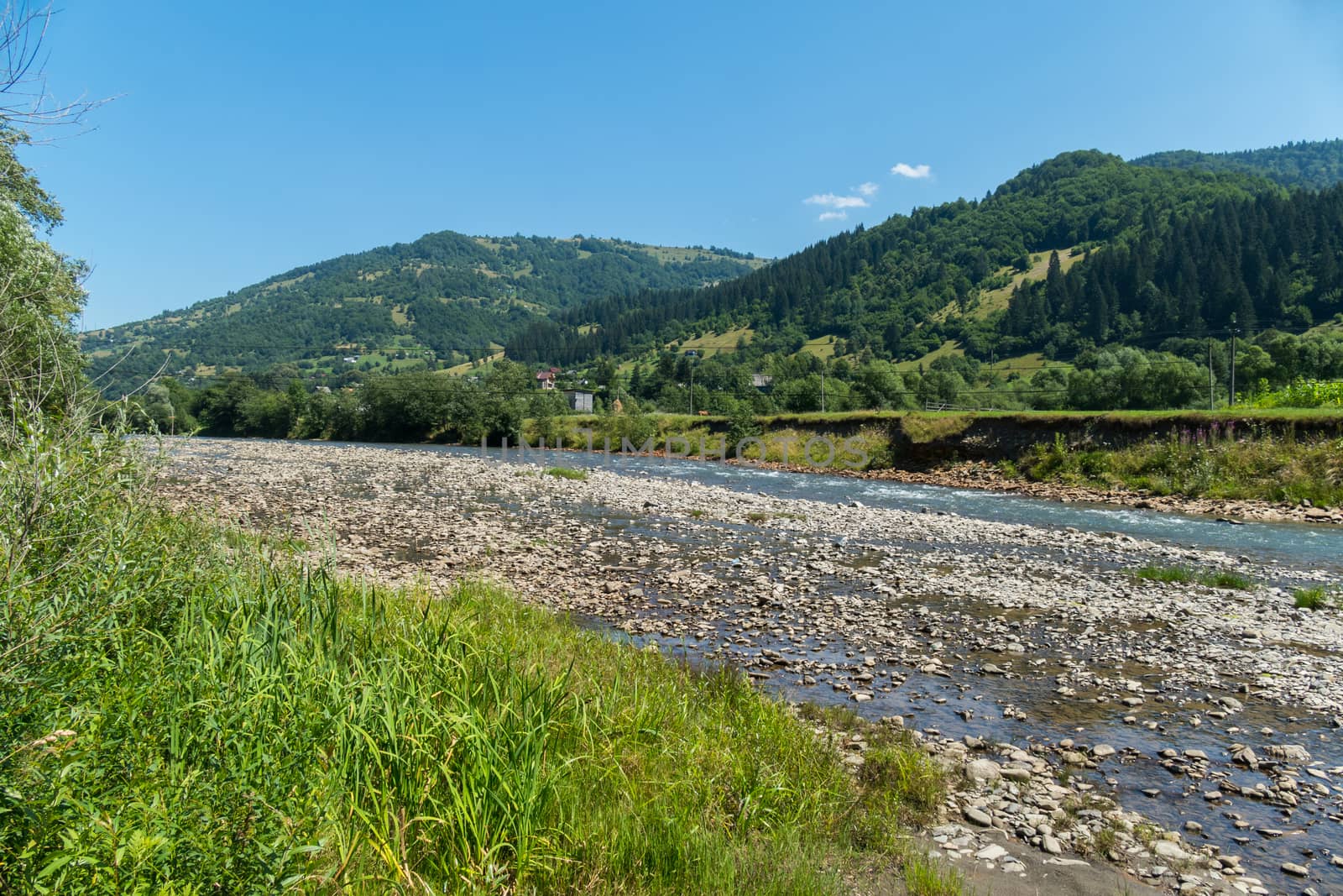 A picturesque view of a shallow mountain river against the backdrop of a beautiful rural village