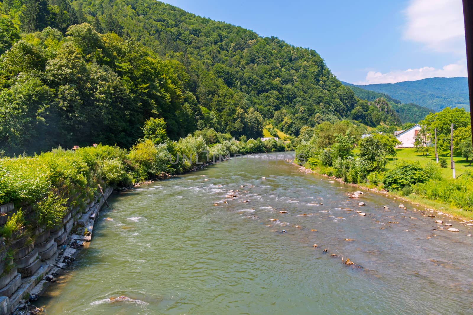 mountain rapid and fast river running between the stones along the green slope