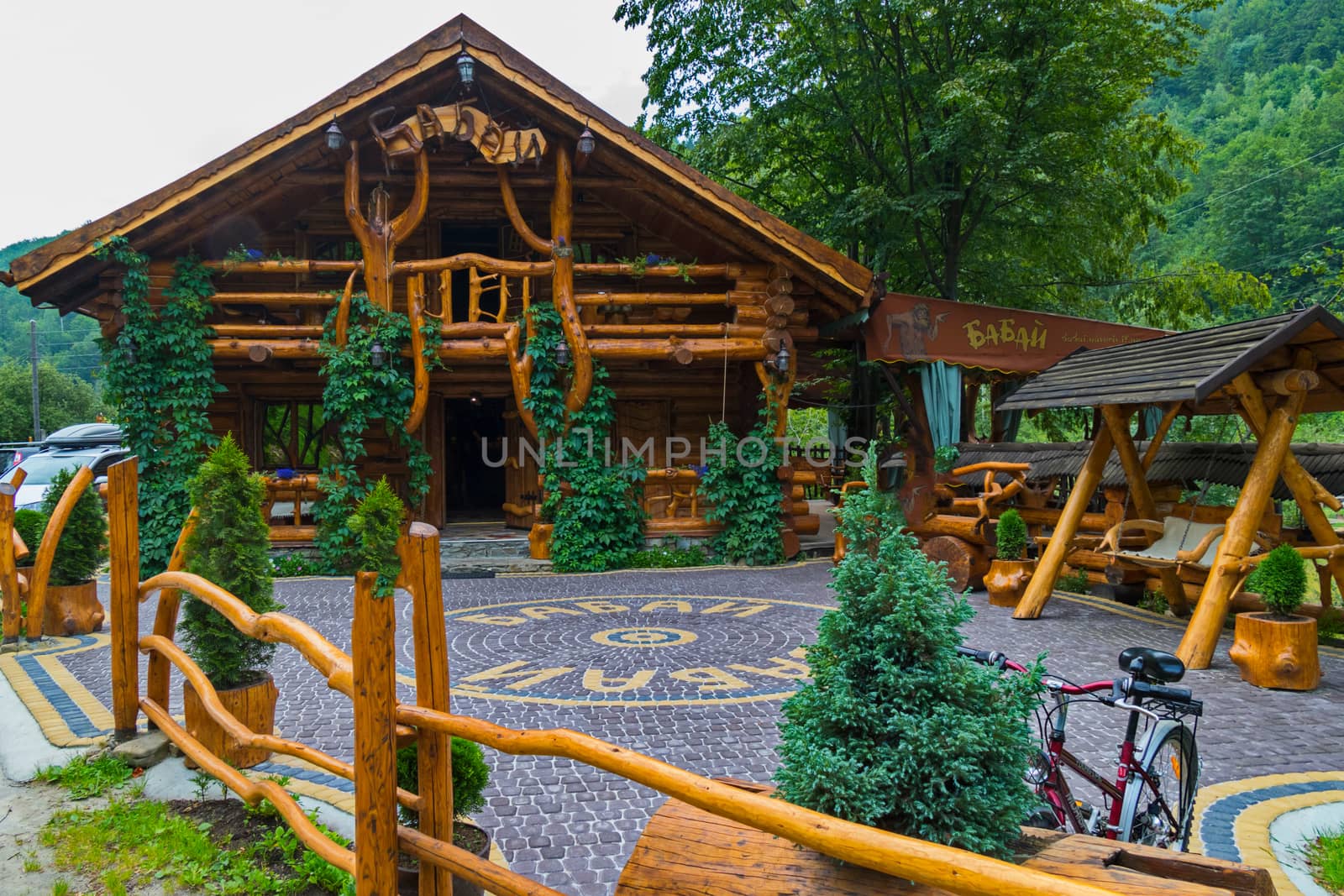 Authentic restaurant complex built of wood and paved with tiles on the background of green mountains. The best place to relax