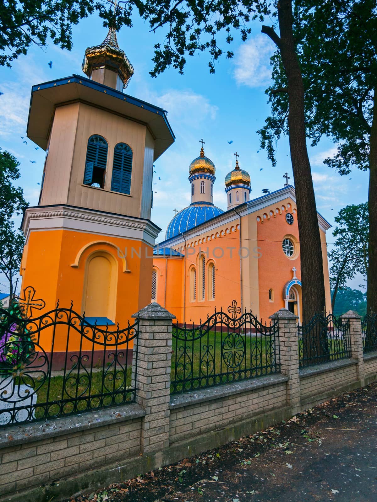 gilding of church domes with crosses on the roof of the church standing behind a low fence with a curved fence