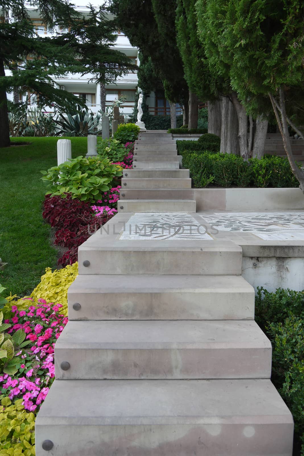 A staircase made of large concrete slabs leading to the house through a flower bed and a lawn with a garden by Adamchuk