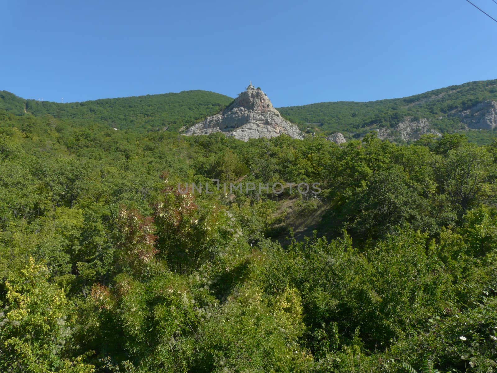 a rocky summit with a monument in the middle of the overgrown trees of the hills