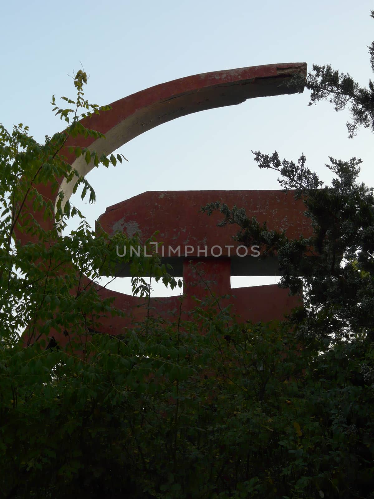 Because of the bushes, a sickle and a hammer is seen as a relic of a previous era. The symbol of communism
