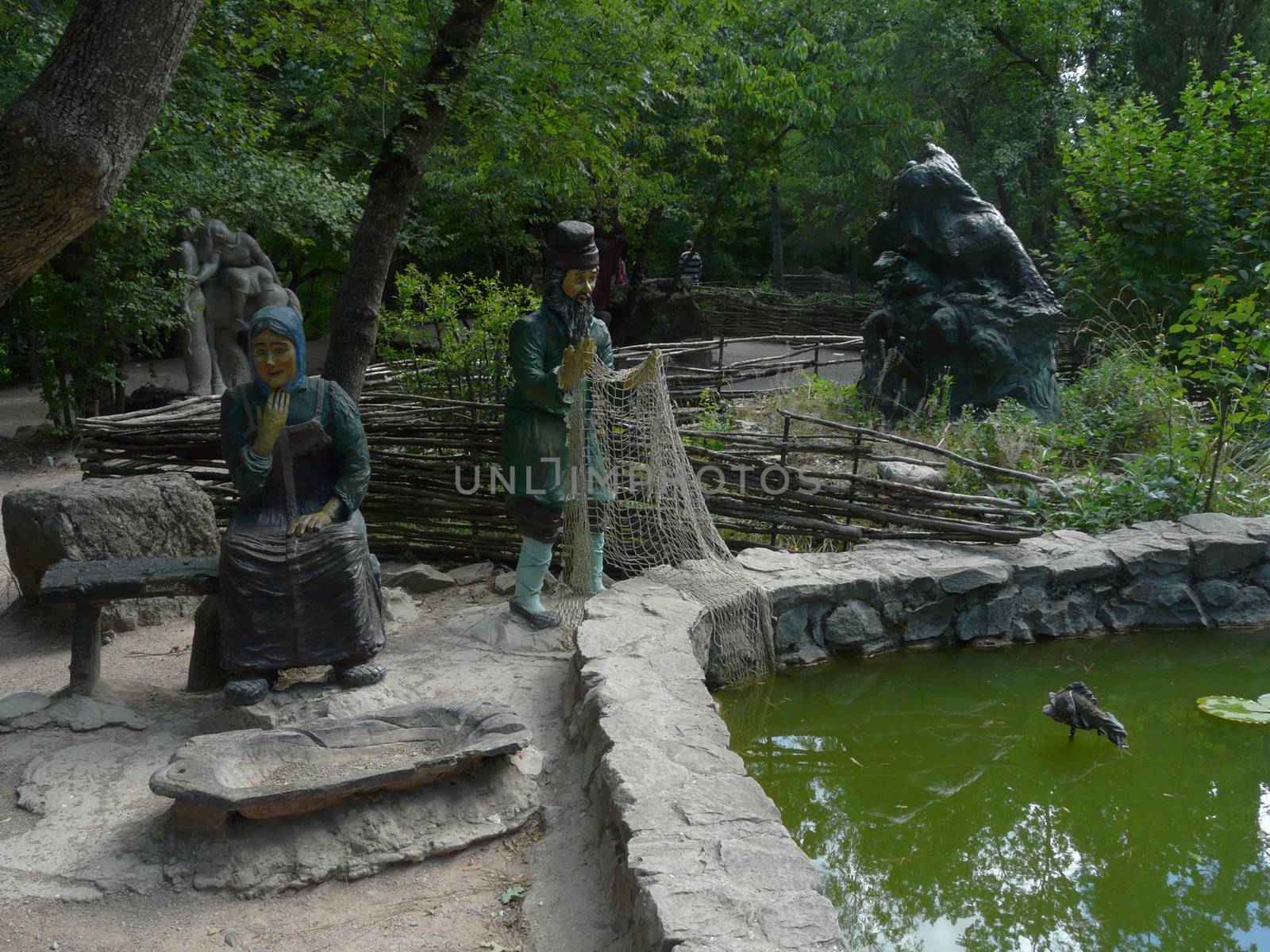 images of a woman and grandfather with a grid of golden fish fairy tale in the park near the lake