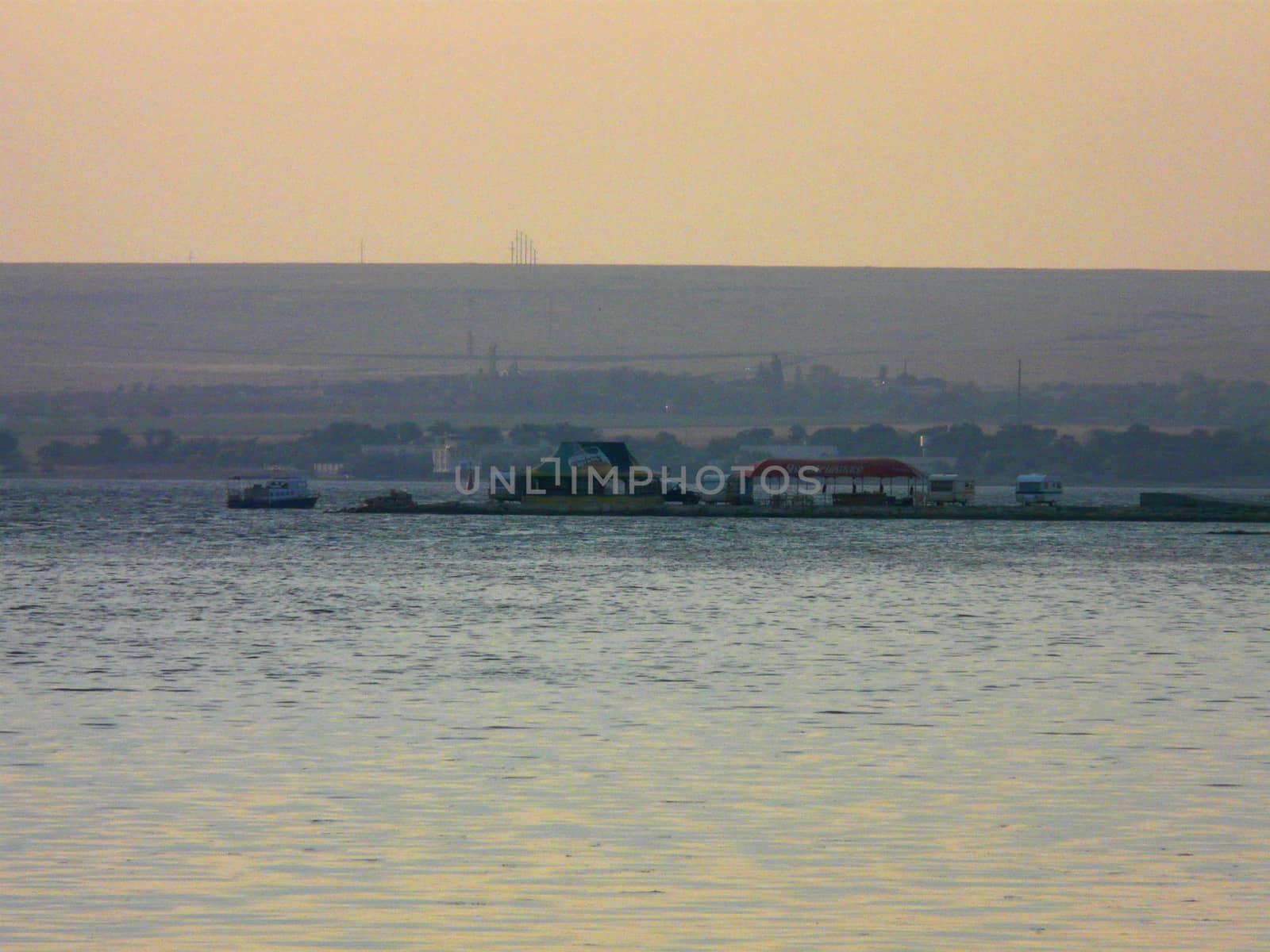 a river surface and a pier with summer cafes and a boat