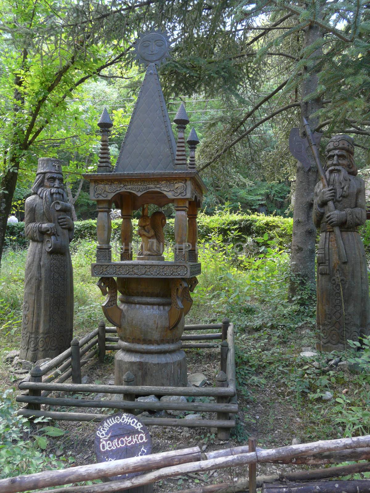 two statues of elders cut from a tree near the wooden carved tower with a squirrel from the fairy tale "About Tsar Saltan" among a thick deciduous forest. a fabulous resting place for the whole family