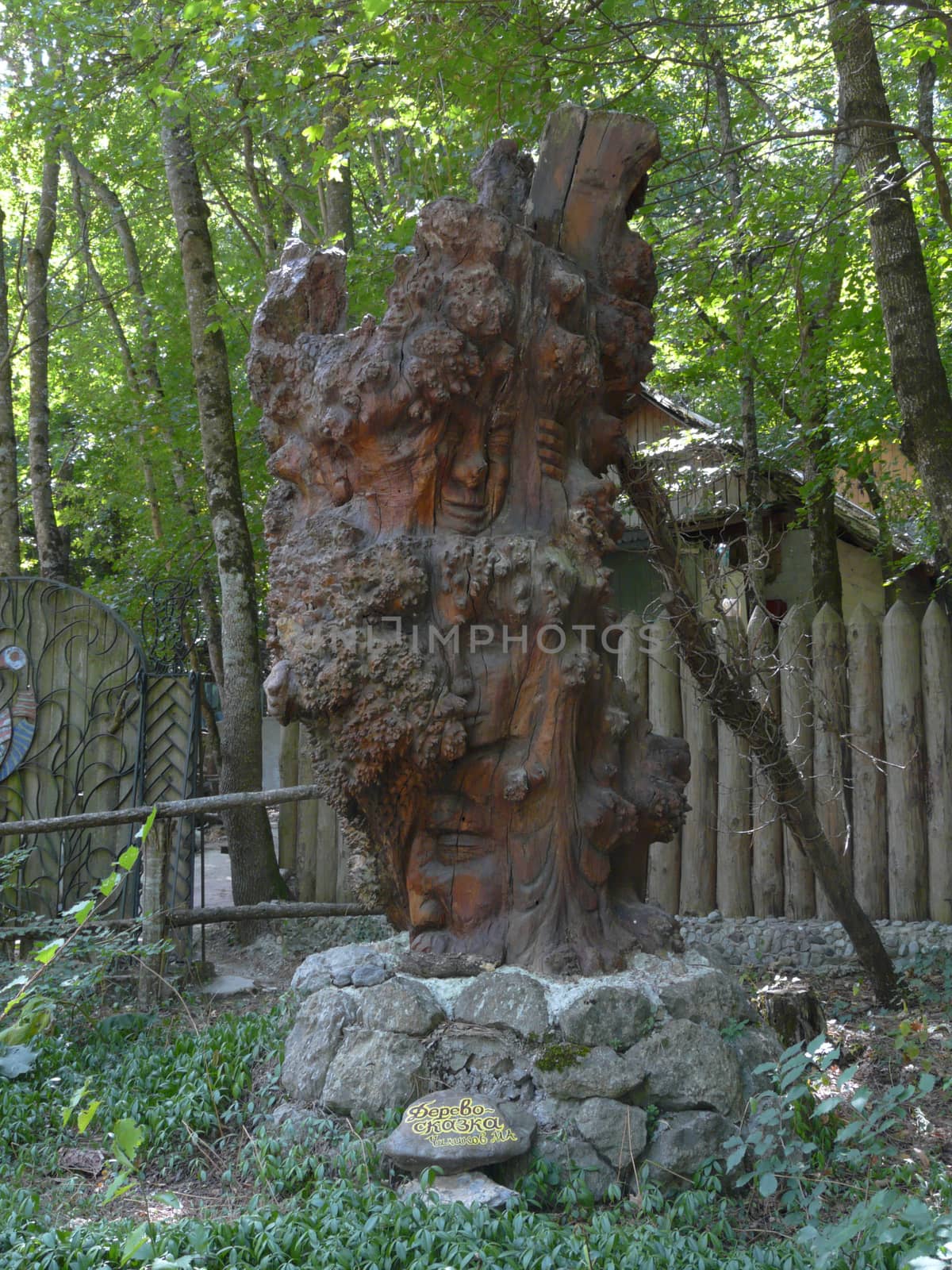A wooden statue is called a fairy tale tree featuring various faces at an exhibition in the park