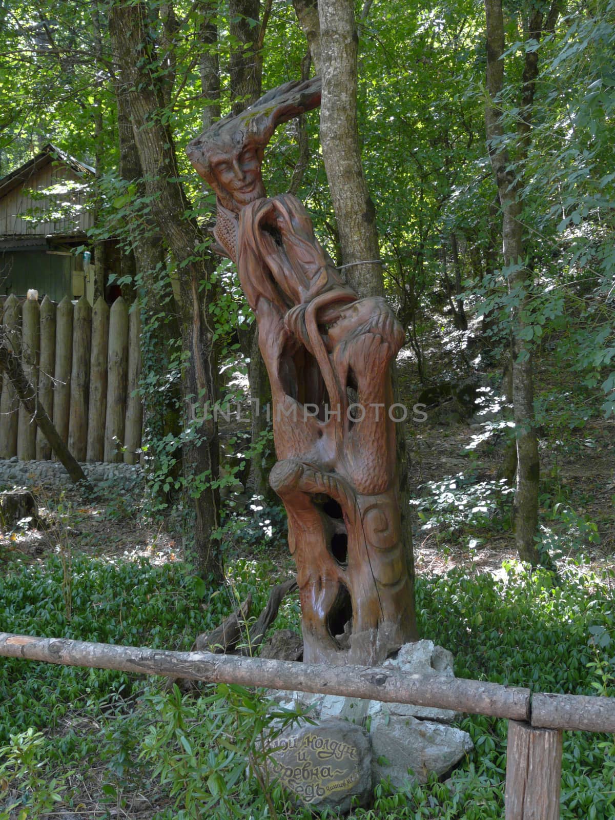 among the green trees on the background of a wooden palisade carved from the tree trunk characters of fairy tales. holiday destination for the whole family