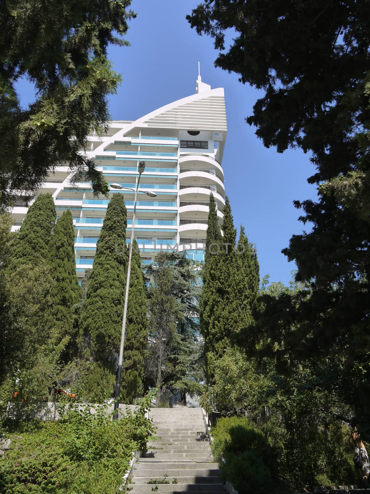 Steps leading to the high modern sanatorium building against the backdrop of lush green cypresses