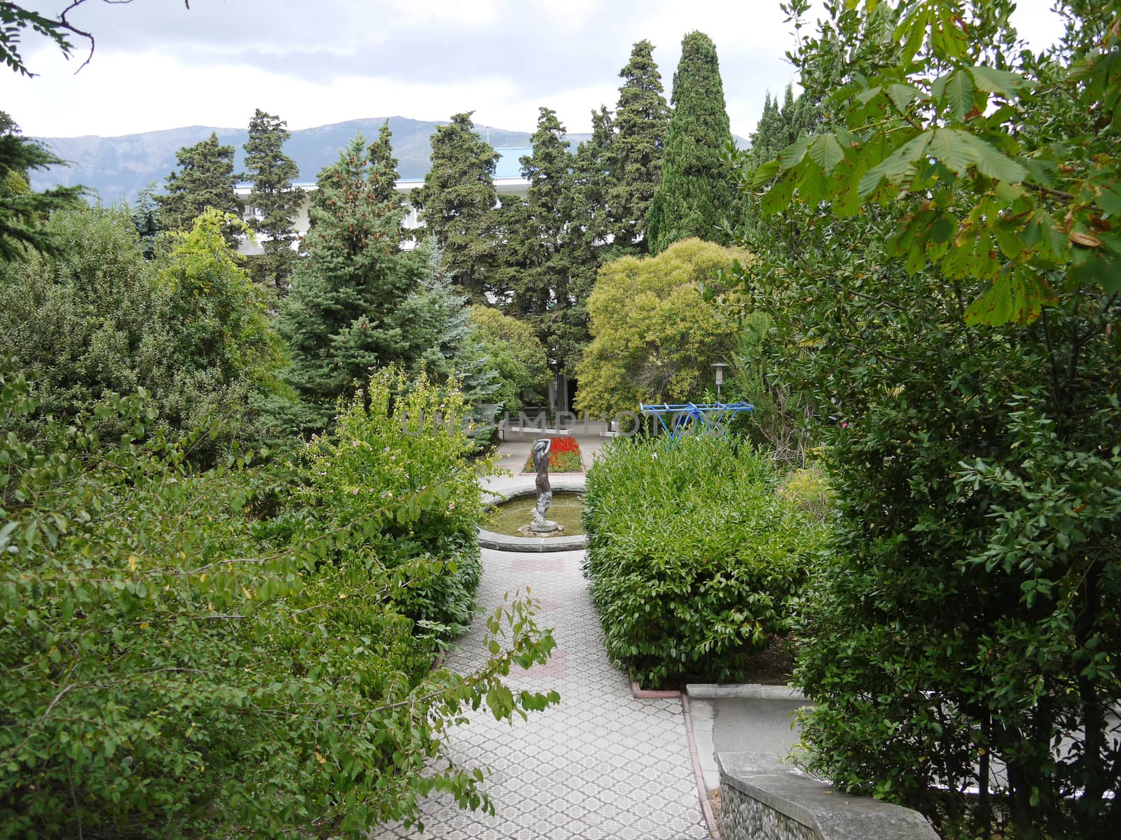 Steps leading to the alley with a fountain in the center and decorative flower beds on either side of it