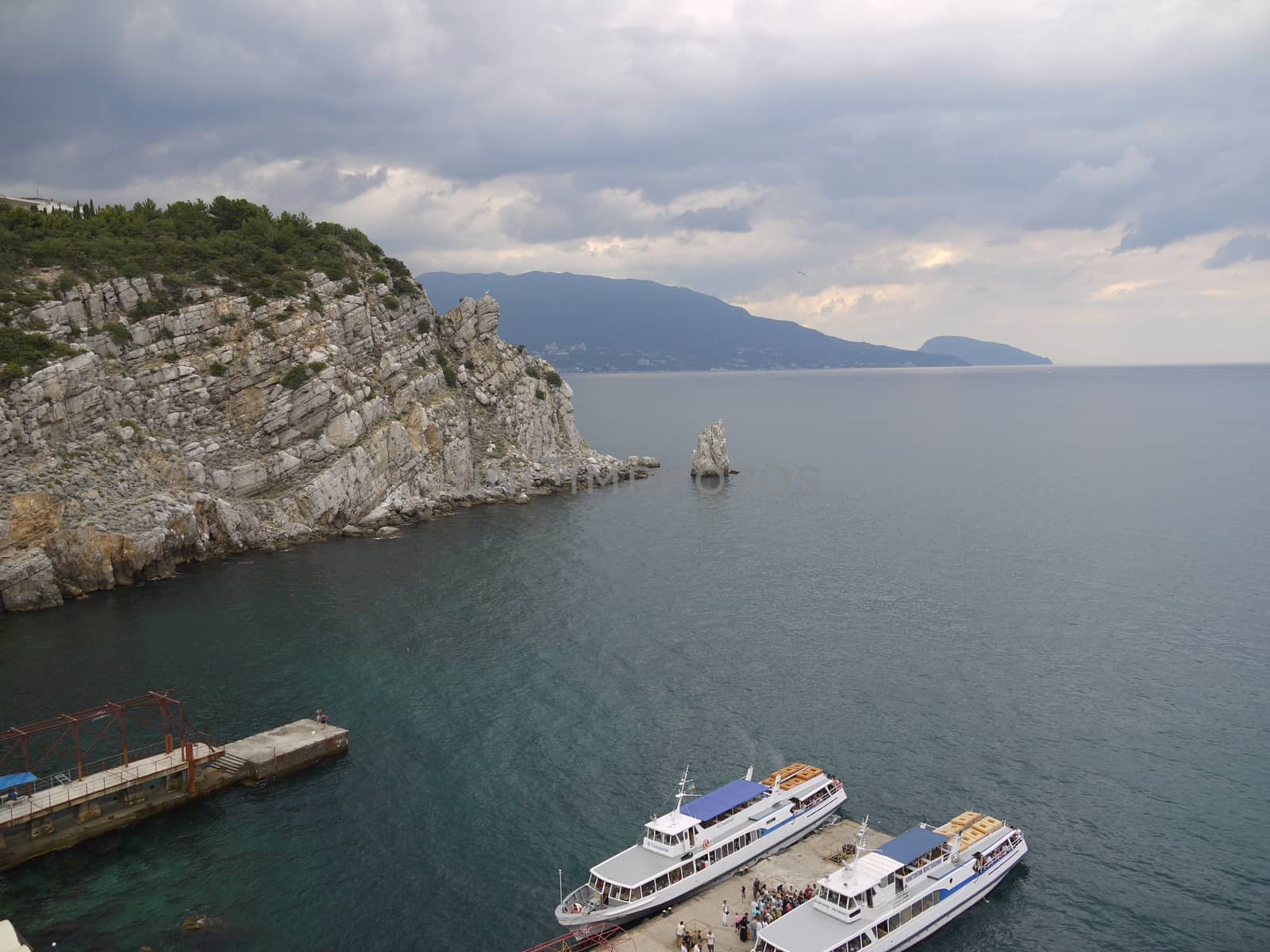 pier with white ships at the foot of a rocky mountain in the black sea