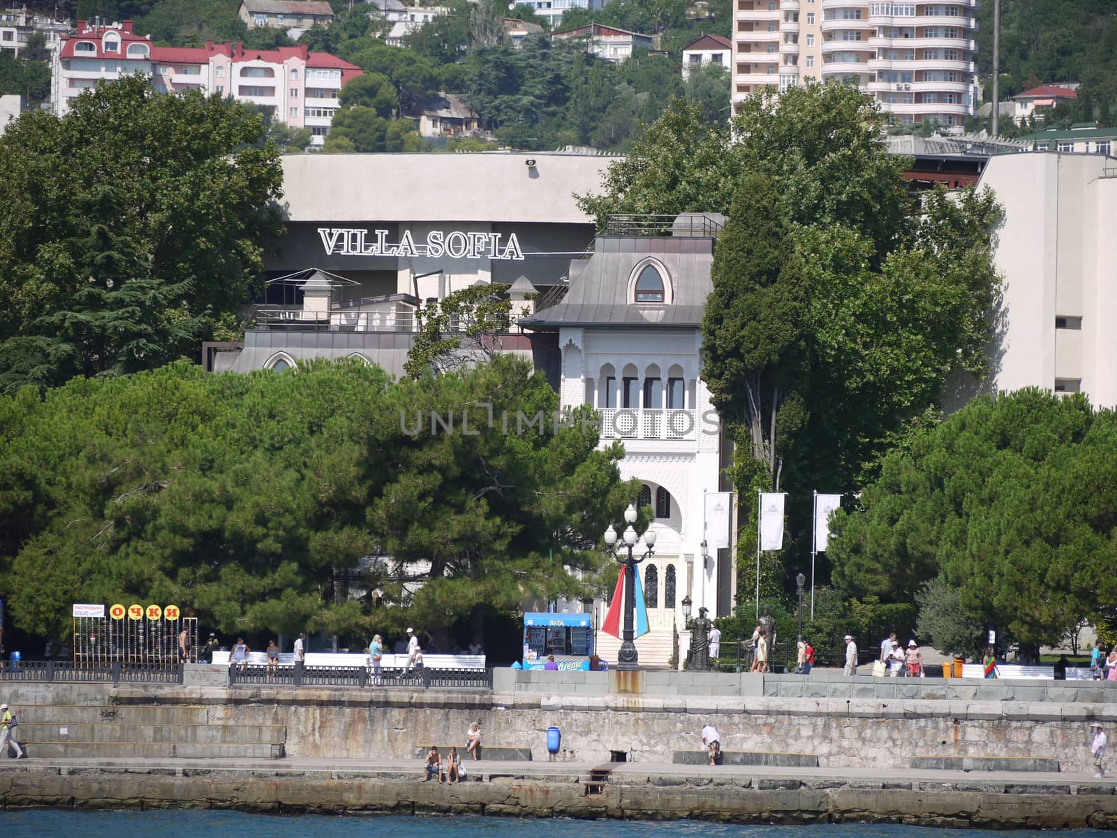 view of the embankment with trees and white hotels from the sea