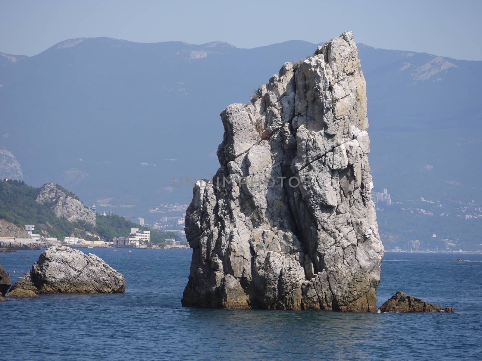 steep rock in the middle of the sea against the backdrop of the mountains