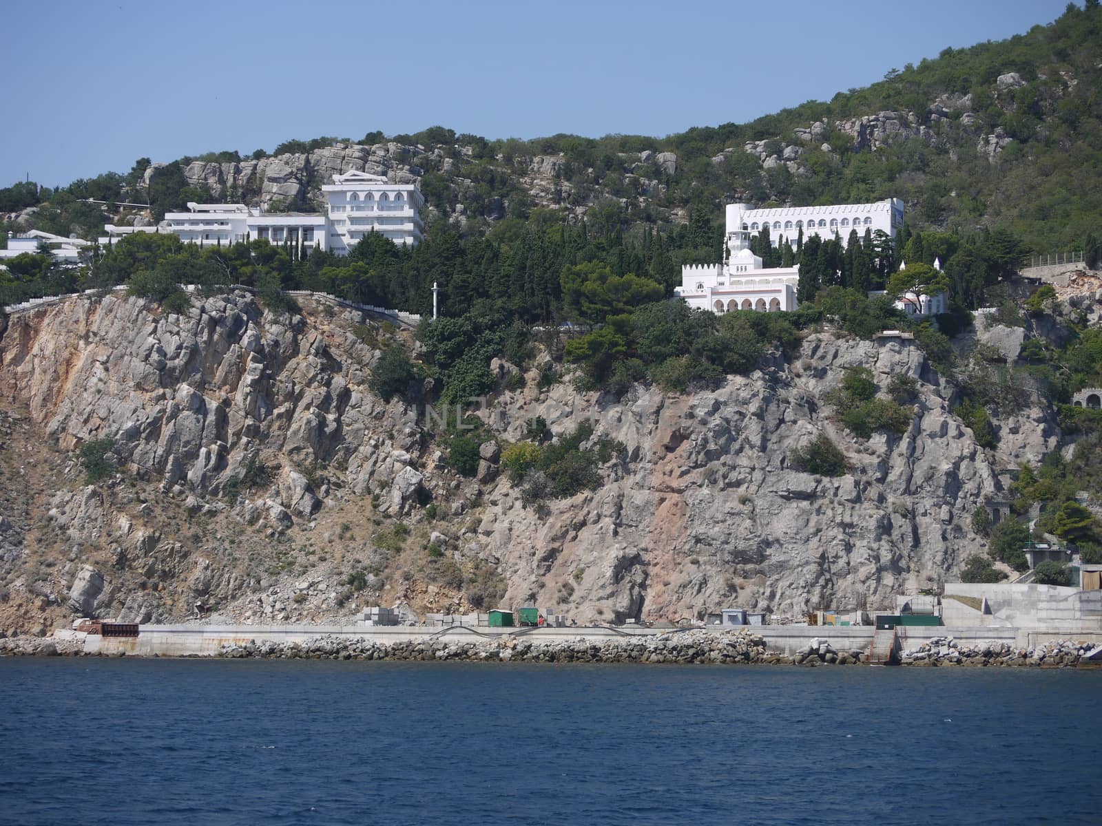 Rocky coastal zone with white houses, gray stones and green trees