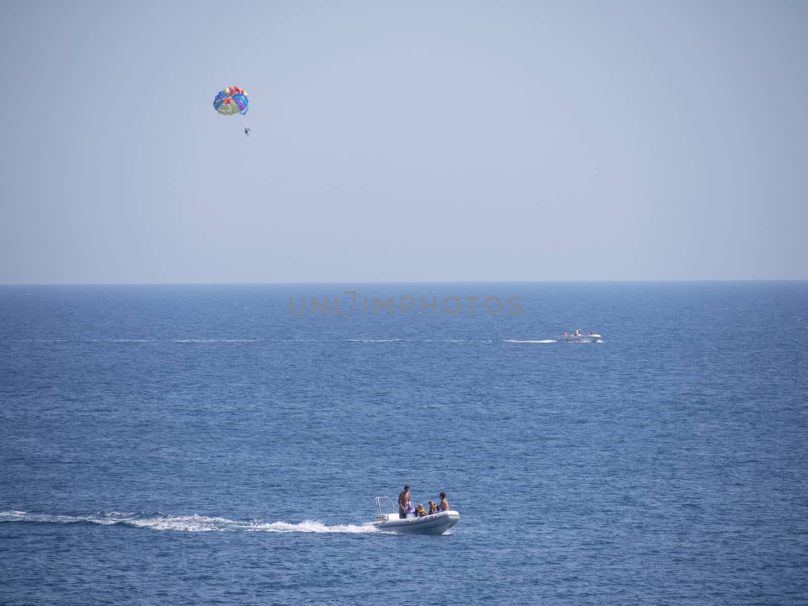 boat with a man on a parachute and a motor boat in the middle of the sea