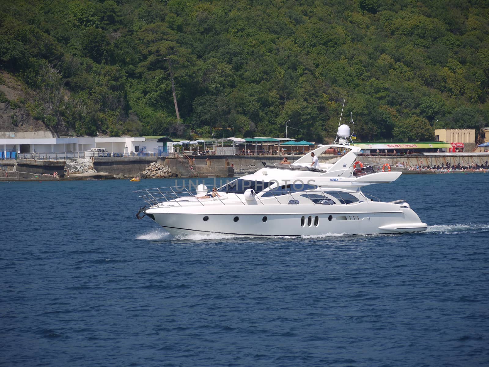 White chic yacht with holidaymakers on the background of the sea resort waterfront
