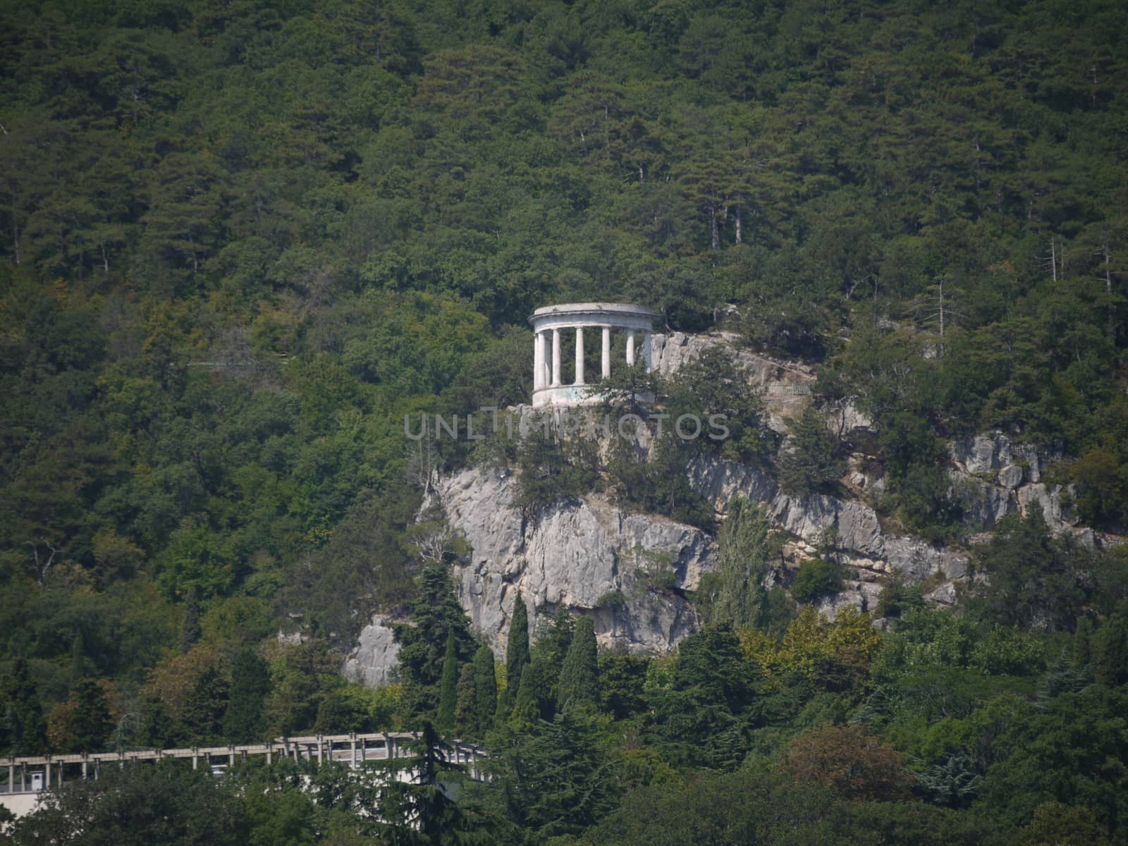 White arbor on a large rock, and around a green sea of trees