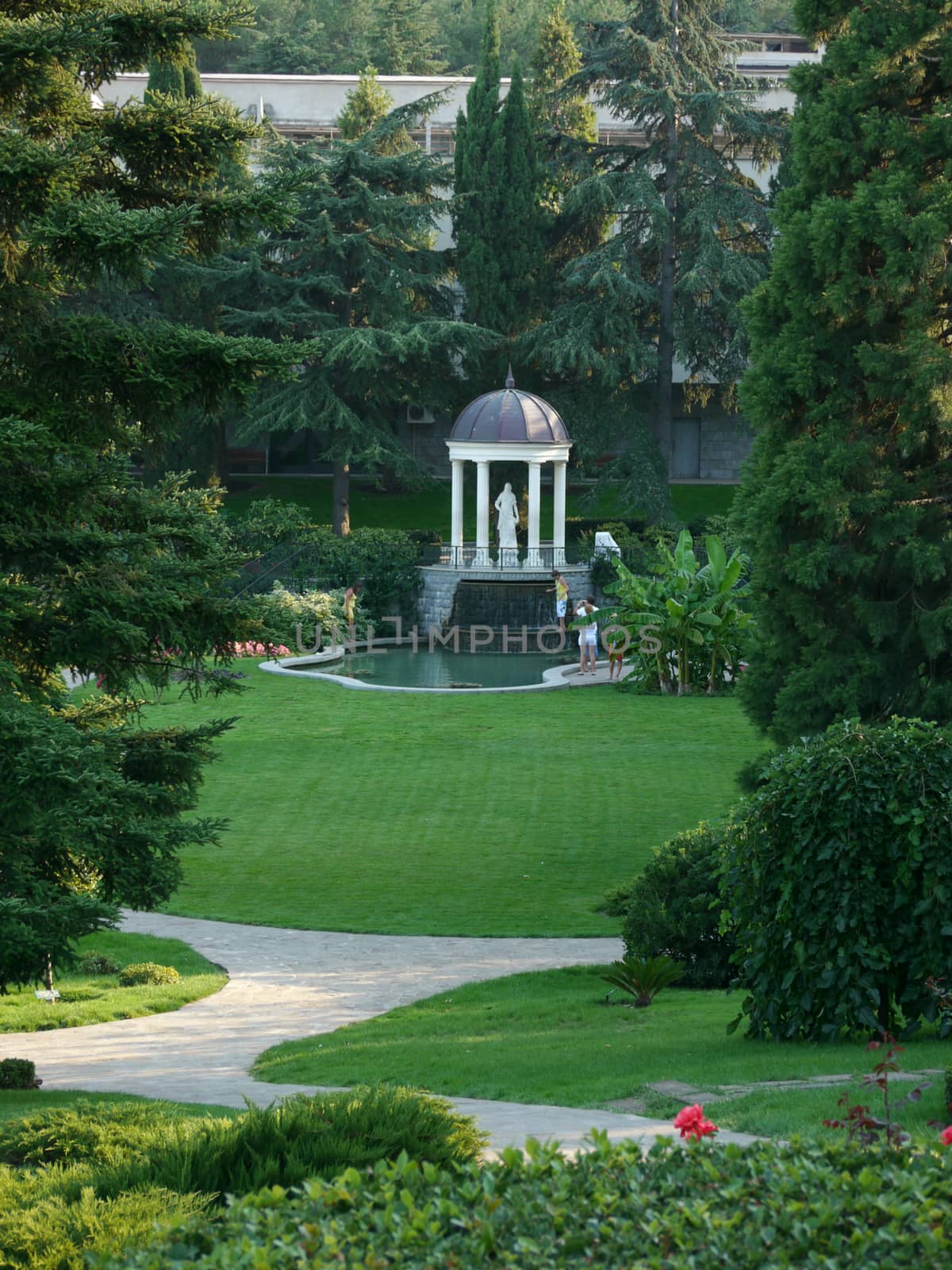 Monument statue under the dome near the lake in a green, clean park