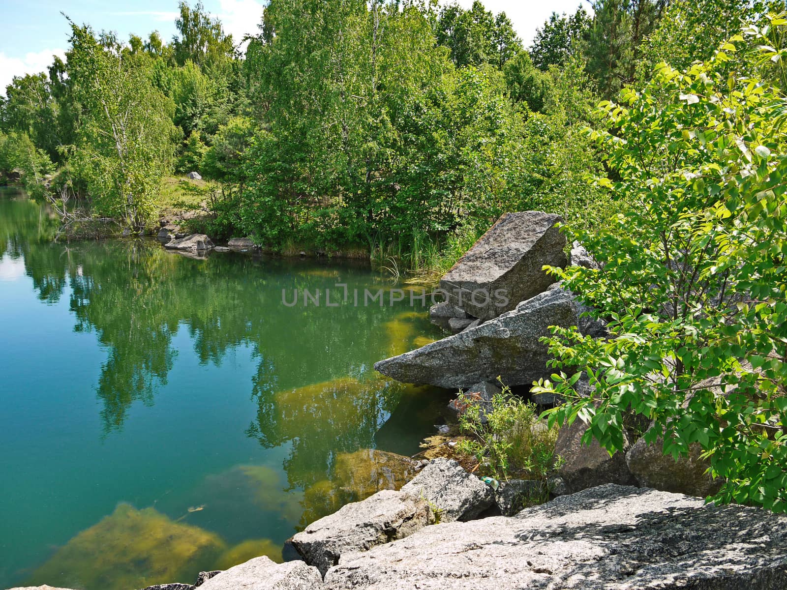 Rocky coast with large stone boulders at the transparent deep blue river