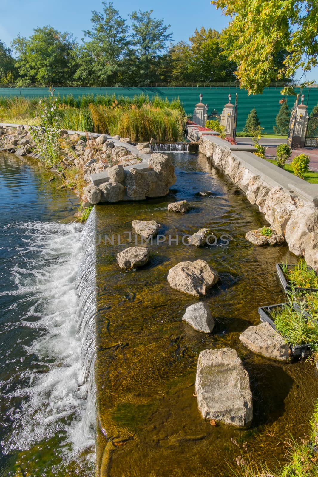 water cascades on an artificial lake with rocky shores near the alley in the park