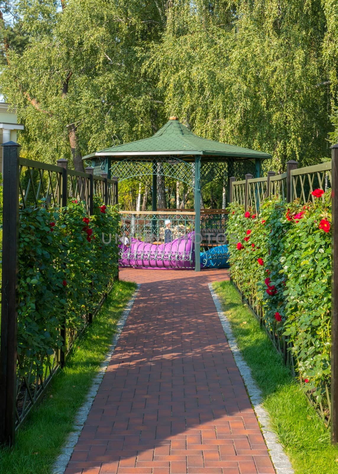 Alley leading to a beautiful decorative gazebo with a green roof and a fence