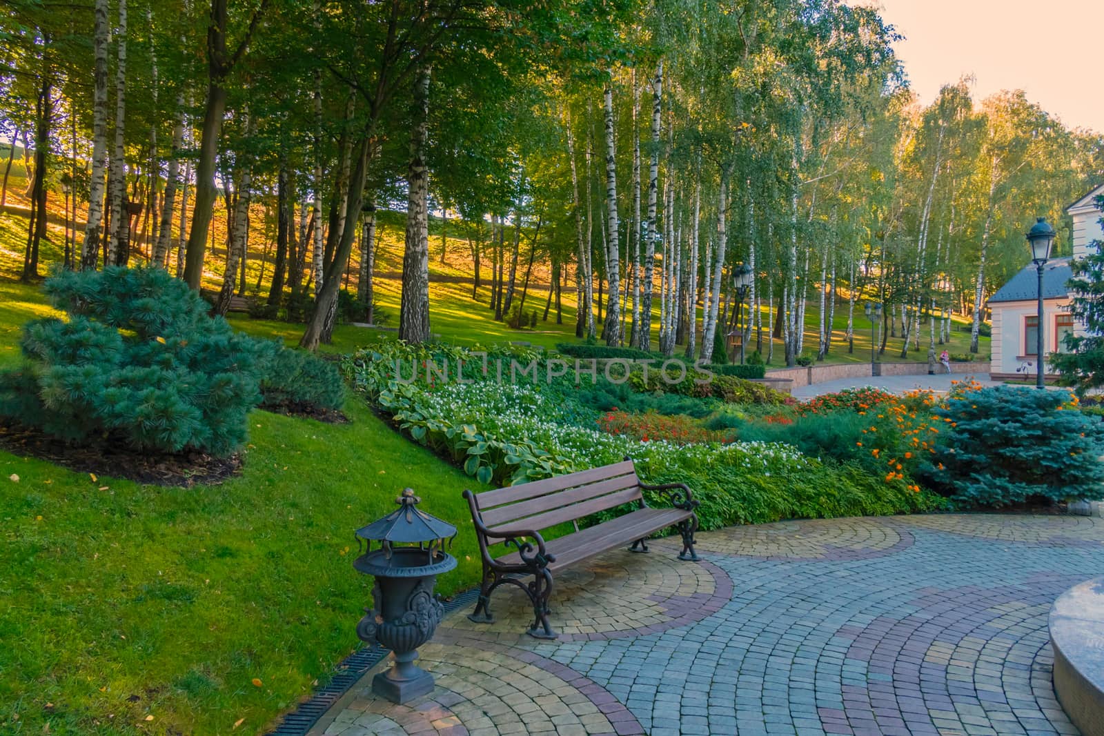 Wooden bench with wrought decorative railing against a background of a slope with flower beds