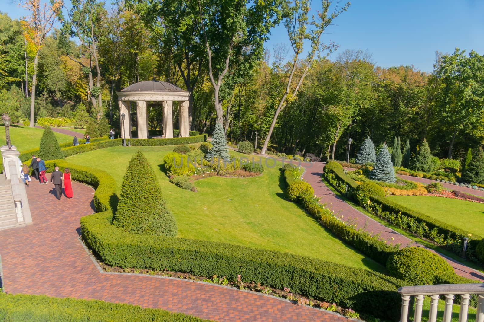 Beautiful view in the park from the hill to the landscape lawn with walking people on the tracks resting people in a good mood.