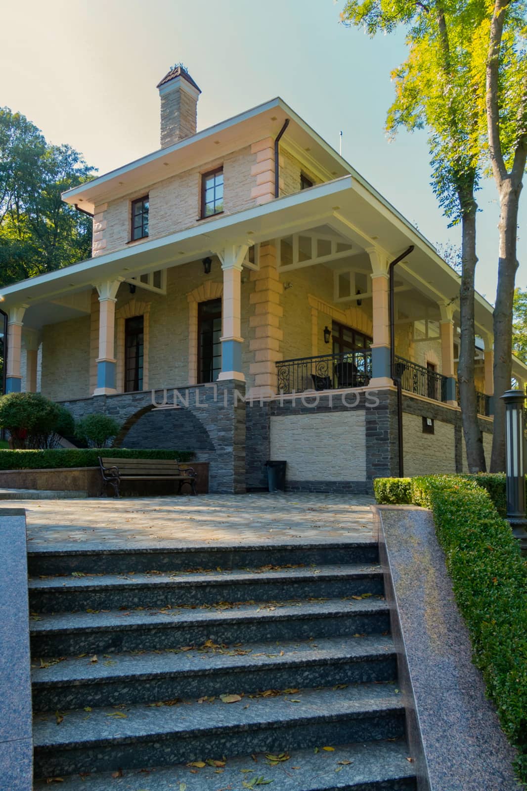 stone house with beige columns and steps in the foreground