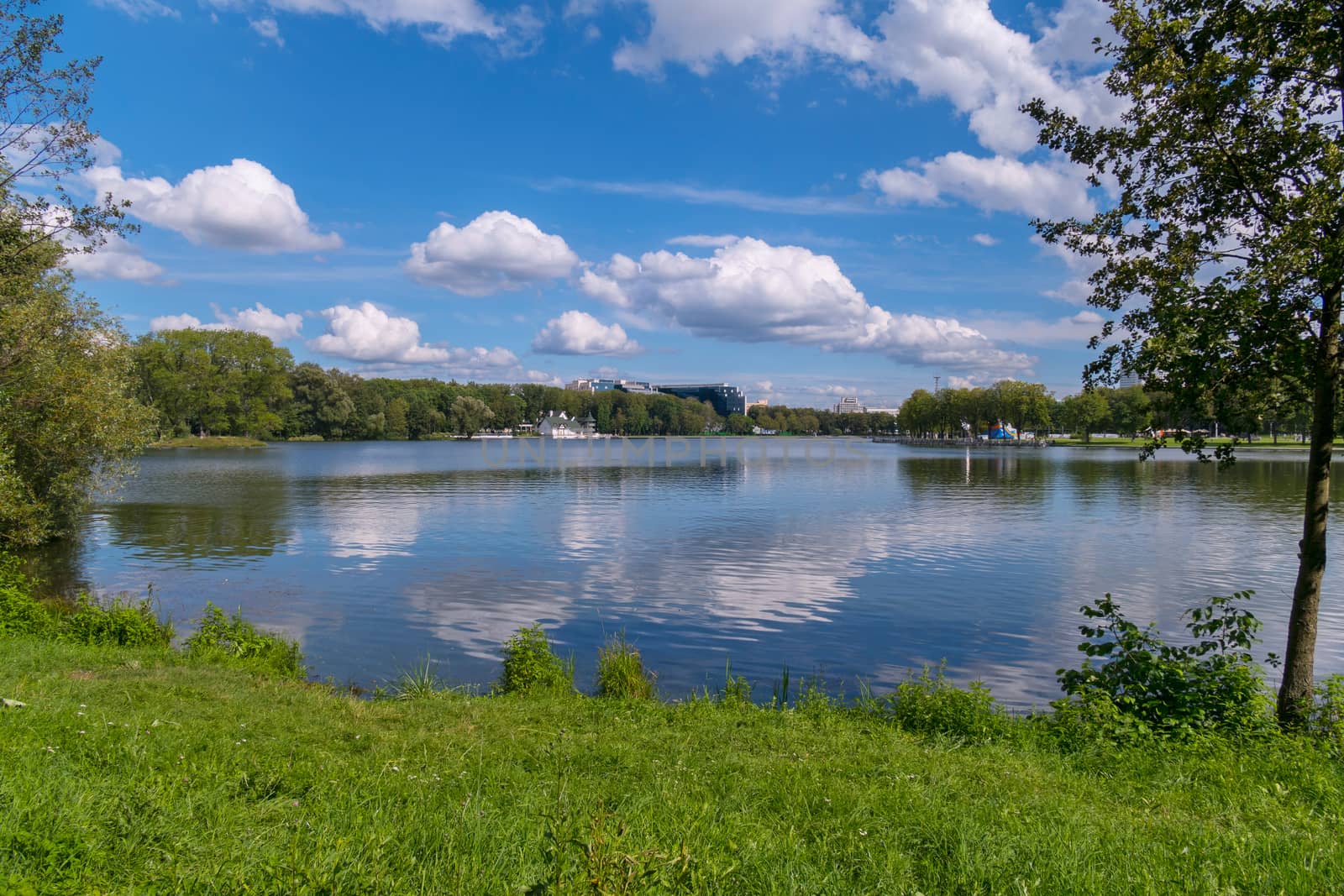 fluffy white clouds float through the blue sky over the calm flat water