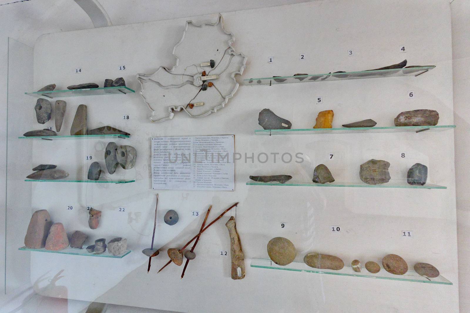 Museum exposition with numbered tools of ancient world work behind glass