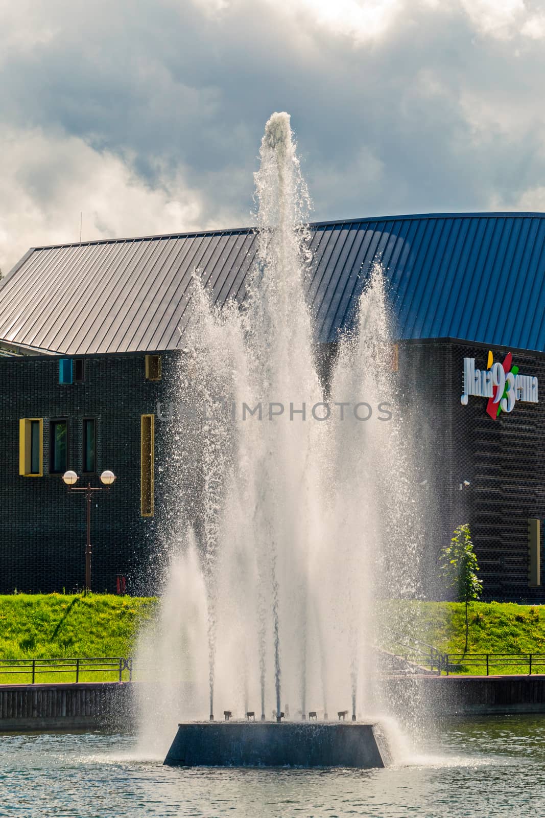 a fountain with clear water, its jet reaching the clouds over the low-hanging sky